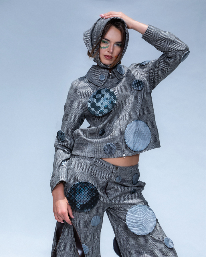 Female model posing with one hand on her head in a matching patterned two piece set against a blue backdrop